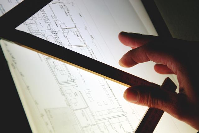 Hand pointing at architectural blueprints on a light table in a Markham design studio