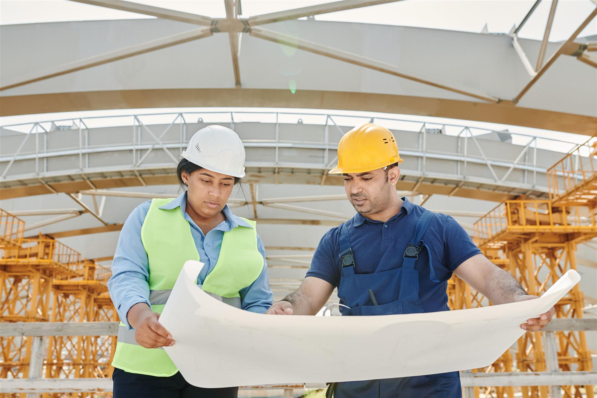 Construction professionals in safety gear reviewing blueprints on a jobsite, managed IT support for construction firms in Vaughan